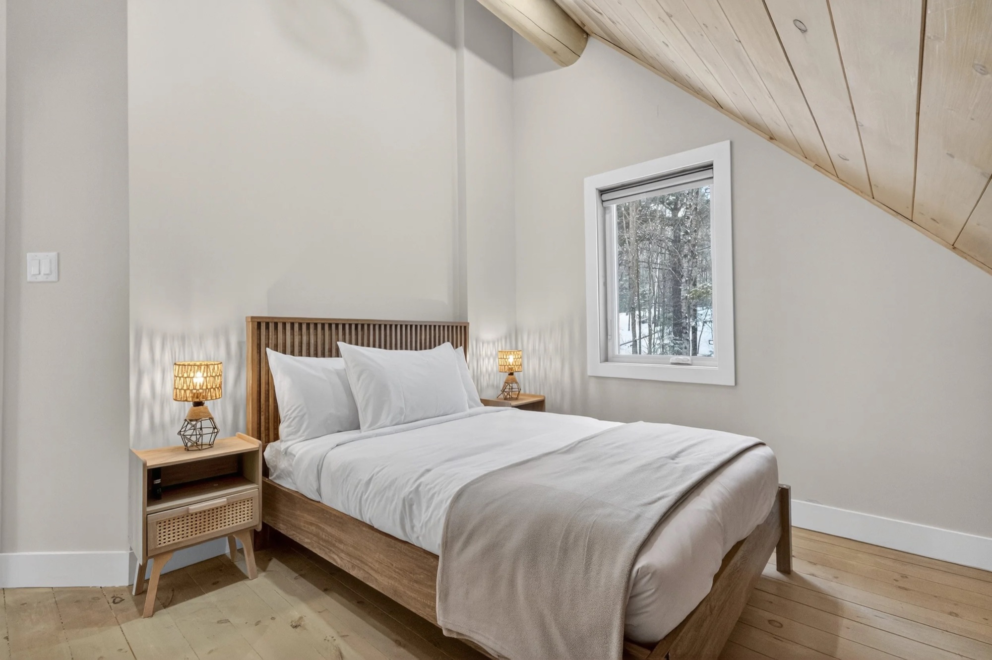 Bedroom 5 — double bed with sloped ceiling and forest views