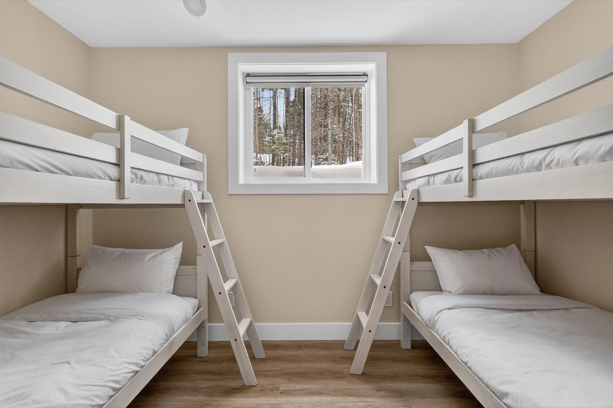 Bedroom 6 — two white bunk beds facing the forest