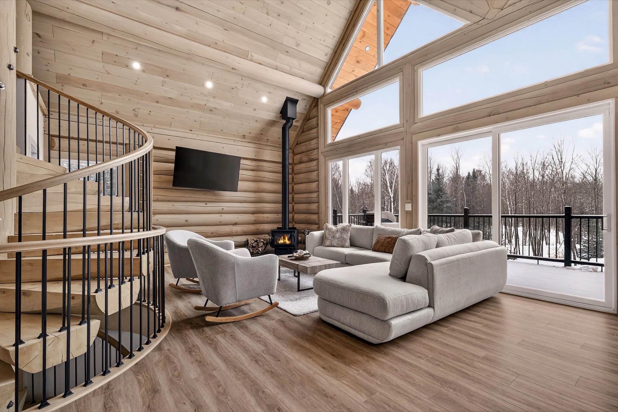 Living room with rocking chairs beside the wood stove and snowy forest views