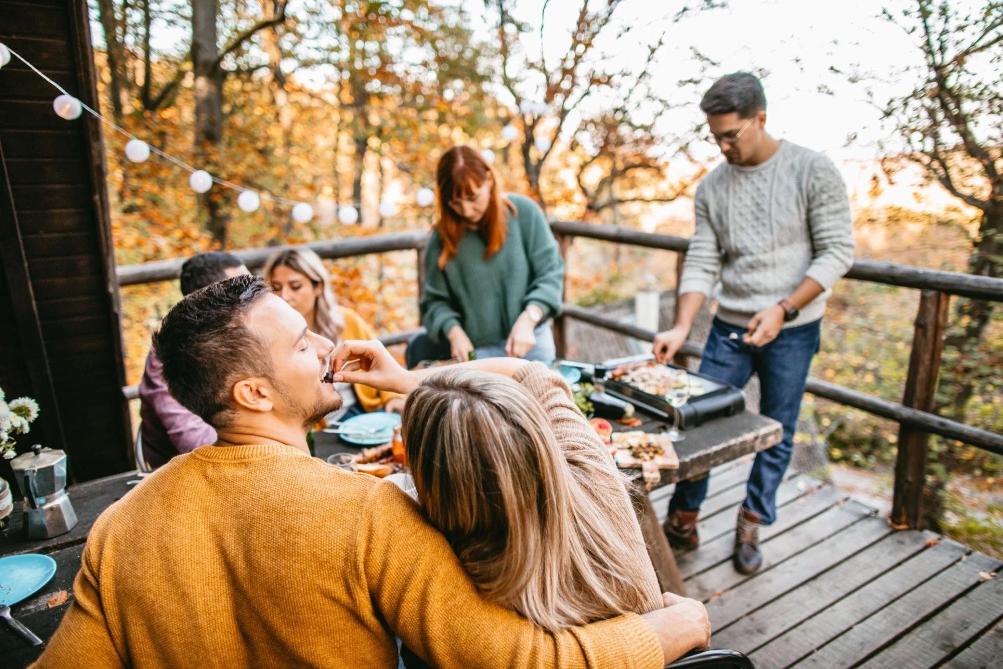 Friends sharing a meal on the balcony surrounded by fall colours