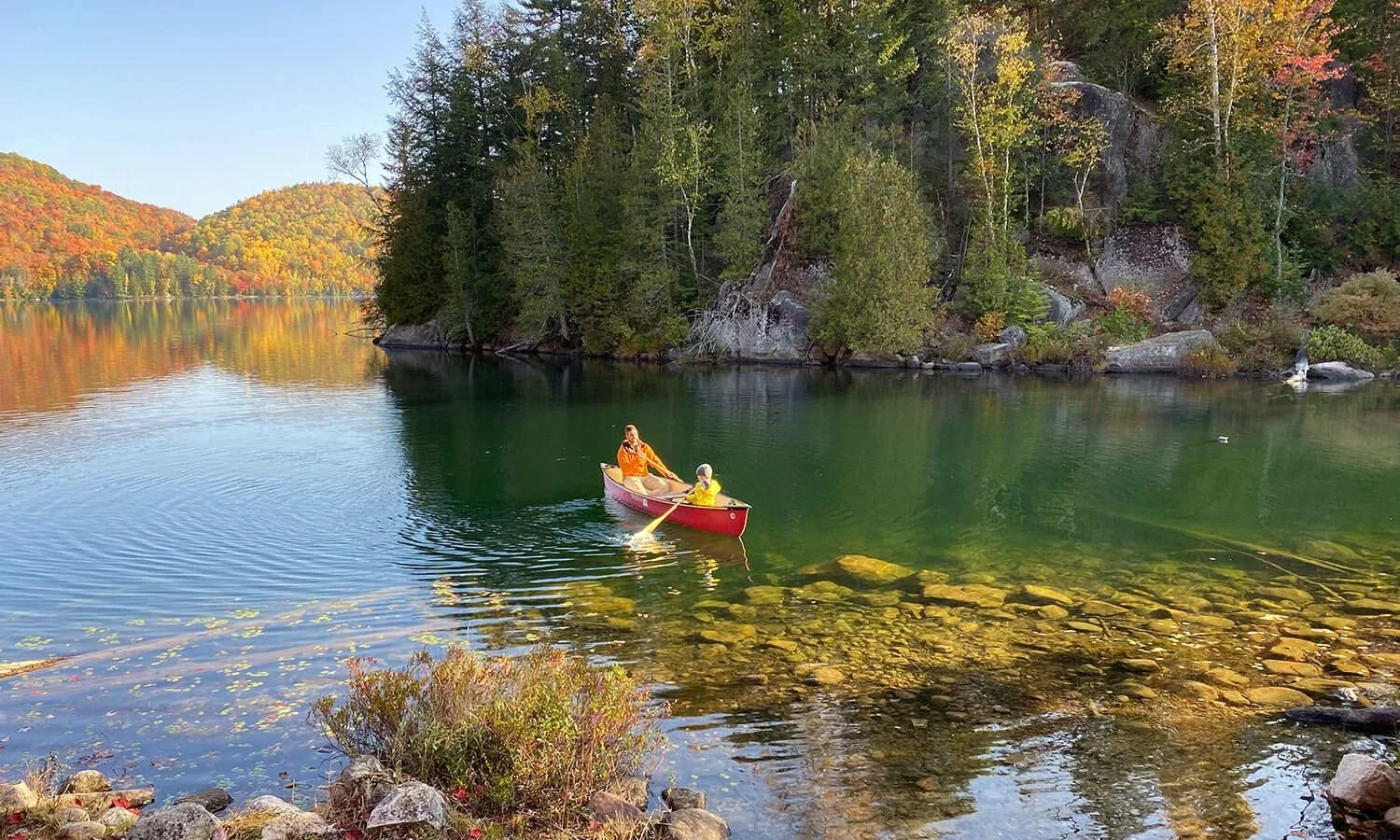 Red canoe drifting on a clear estate lake